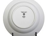 a white plate with a bird on it on a stand