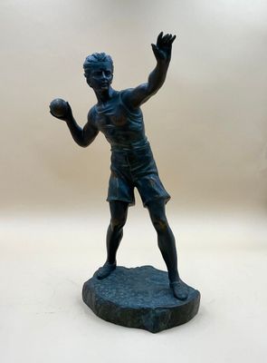 une statue représentant un homme en train de lancer une balle sur une surface blanche