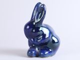 a small blue rabbit figurine sitting on a white surface