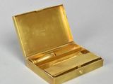 a small gold box with a pair of scissors in it