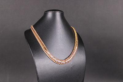un collier à chaîne en or sur un mannequin, sur fond noir