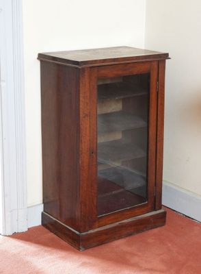 une petite armoire en bois avec une porte vitrée, dans un coin