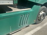 a green semi truck with a flat bed on the road
