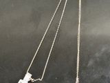 un collier en argent orné d'une pierre bleue et d'une plaque portant un nom