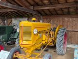 un gros tracteur jaune garé à l'intérieur d'une grange