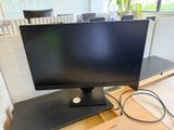 un écran d'ordinateur posé sur un bureau en bois
