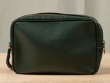 a green leather toilet bag sitting on top of a wooden table