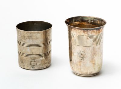 two silver cups sitting next to each other on a white surface