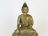 brass statue of a seated buddha on a white background