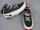 pair of black and white sneakers with red soles on a gray surface