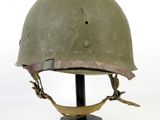 an old green helmet on a black stand on a white background