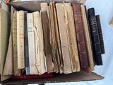 a box full of old books sitting on a bed
