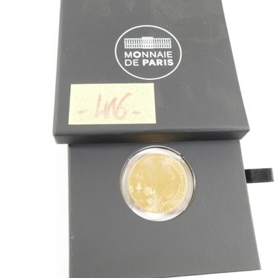 La pièce se trouve dans une boîte noire sur laquelle est collé un autocollant.