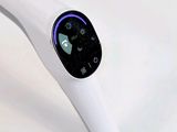 a white electric toothbrush with a blue light on it