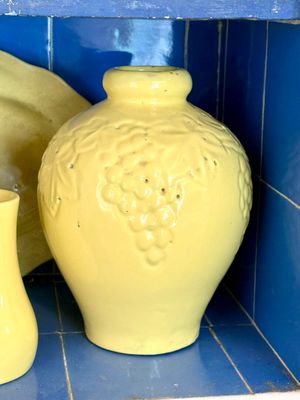 deux vases jaunes posés sur une étagère dans une pièce carrelée de bleu