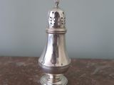a silver pepper shaker sitting on a marble table