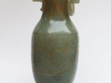 un vase vert posé sur une surface blanche