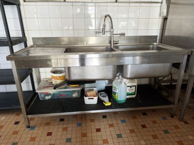 a stainless steel sink in the middle of a tiled floor