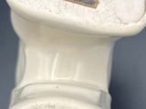 a small white vase with a label on it