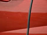 a close up of a red car with a bird perched on the door handle