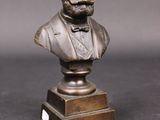 un buste en bronze représentant un homme barbu portant un nœud papillon