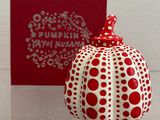 un bibelot rouge et blanc posé sur une table, à côté d'une boîte rouge