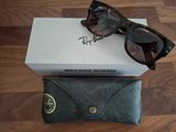 Des lunettes de soleil Ray-Ban et leur étui posés sur un parquet