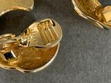 a pair of gold earrings that are on a table