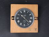 une horloge posée sur un bloc de bois, avec des chiffres romains