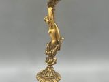 an antique brass candelab with three candles and a bird on it