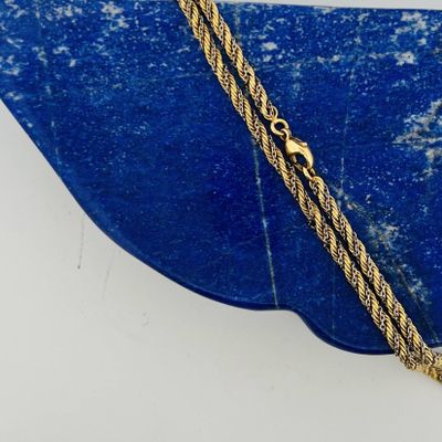 an image of a gold plated necklace on a blue stone