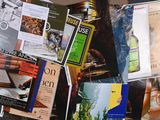 a bunch of magazines on a table with a bottle of wine