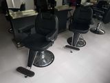 several black chairs are lined up in a row in a hair salon