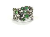 a close up of a ring with green stones on it
