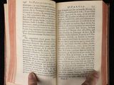 someone is holding a book in their hand on a black surface