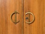 a close up of a door handle on a wooden cabinet