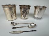 quatre tasses et cuillères en argent posées sur une table