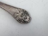 a silver spoon with a handle on a white surface