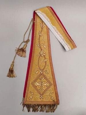 une image représentant une étole dorée et rouge, avec des pompons qui pendent sur le côté