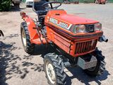 un tracteur rouge garé devant un bâtiment vert