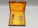 six forks in a wooden box with a gold lining