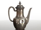 une théière en argent avec son couvercle, posée sur une table