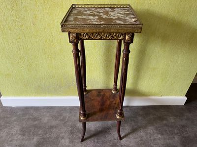 une petite table en bois avec un plateau en marbre, posée sur un sol recouvert de moquette