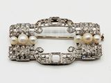 une image représentant une broche ornée de perles et de diamants sur fond blanc