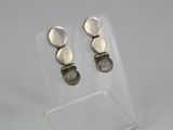 une paire de boucles d'oreilles en argent posée sur le dessus d'une vitrine transparente