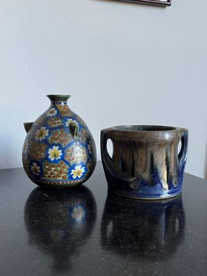 deux vases posés sur une table, avec un tableau accroché au mur en arrière-plan
