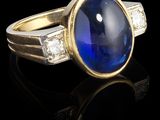 gros plan d'une bague avec une pierre bleue entourée de diamants