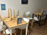 tables and chairs in a room with white walls and wood flooring