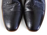 pair of black leather shoes on a white surface with a white background