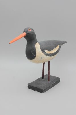 oiseau noir et blanc au bec orange, posé sur un socle noir